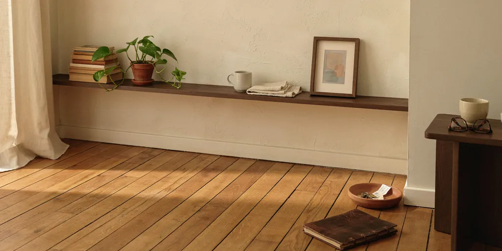 A shelf with a gap in the middle of its objects, a picture propped against the wall rather than hung, and empty plaster beside it