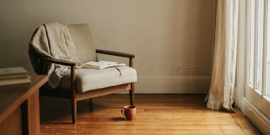A reading chair placed beside a tall window so daylight comes across from the side onto the page