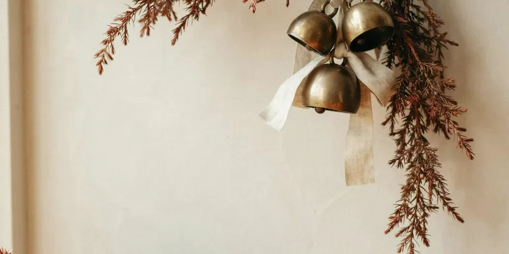 Three small unlacquered brass bells tied on linen ribbon hanging from the end of a cedar garland